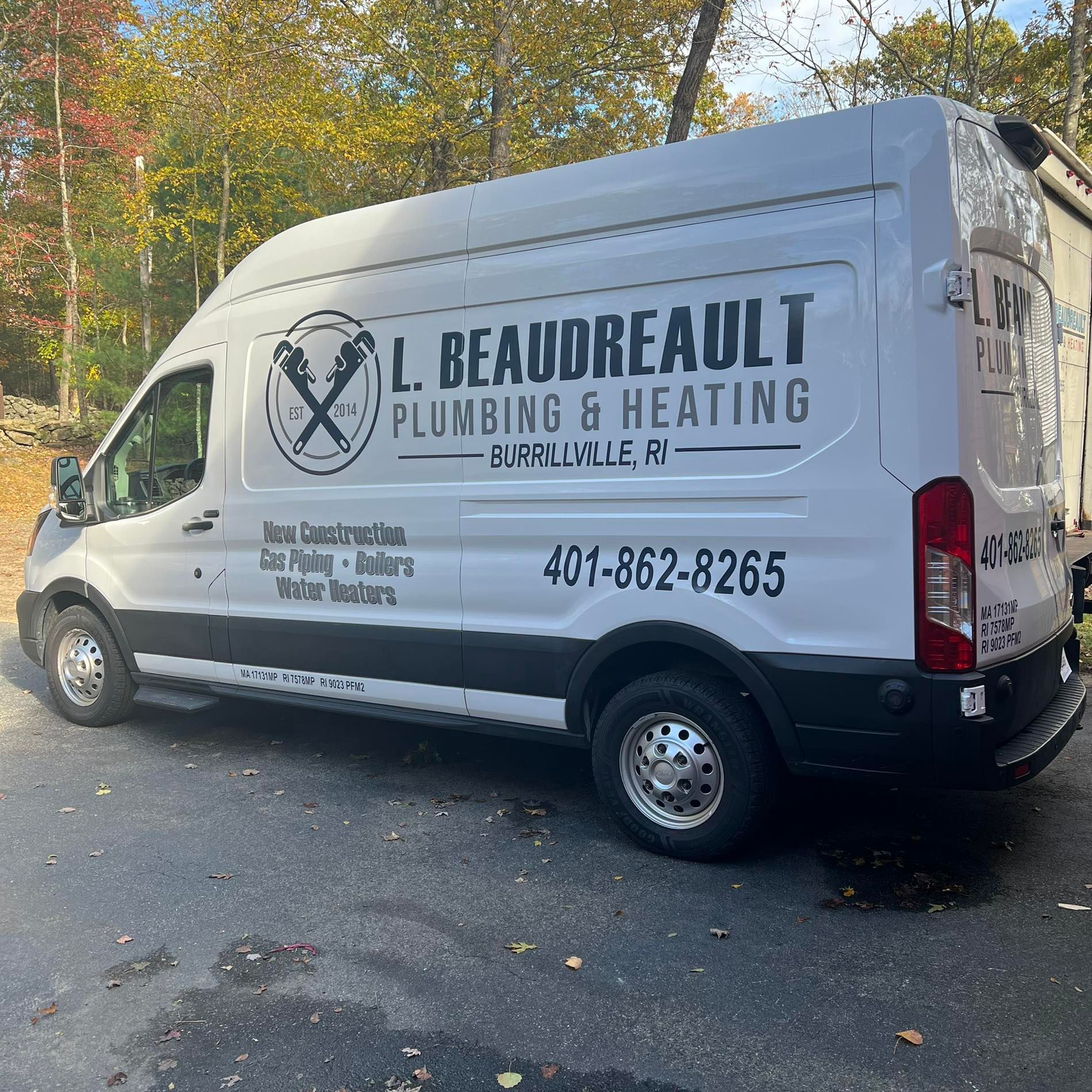 White L. Beaudreault Plumbing & Heating van parked on a tree-lined street in autumn