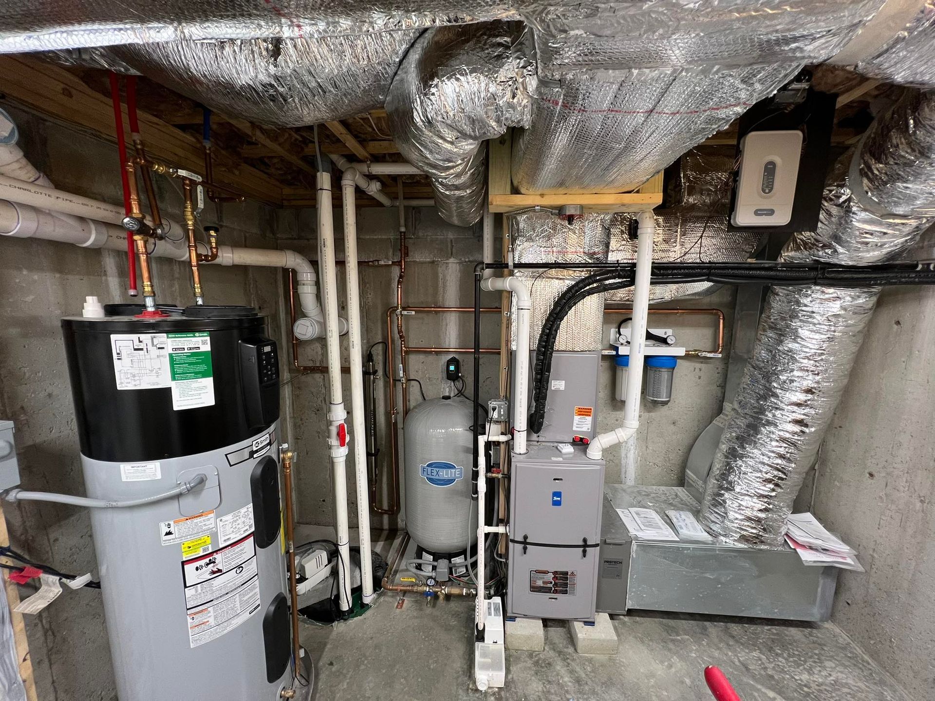 Basement utility room with water heater, furnace, and insulated ducts and pipes.