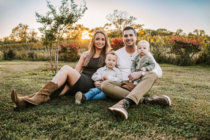 A man and woman are sitting in the grass with a baby.
