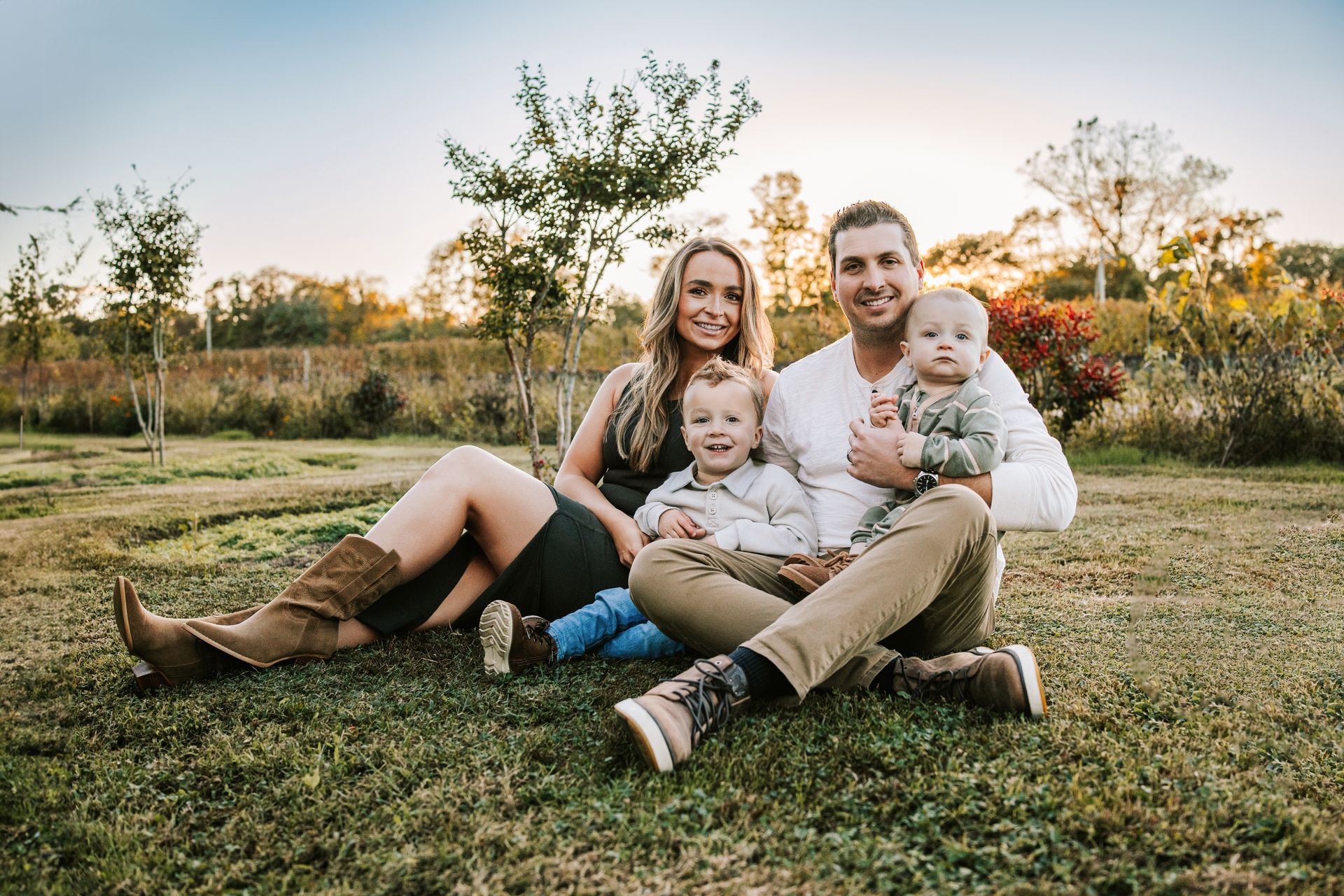 A man and woman are sitting in the grass with a baby.
