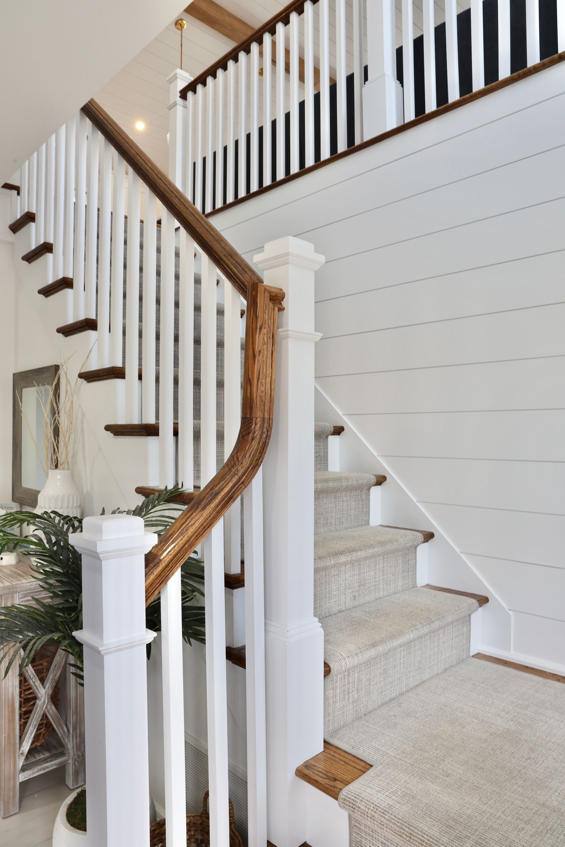 A white staircase with a wooden railing and carpeted steps in a house.