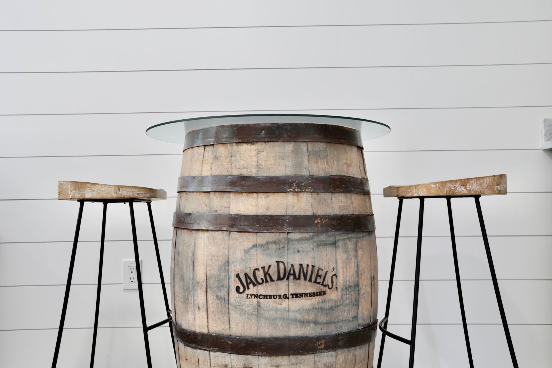 A table made out of a jack daniels barrel with two stools.