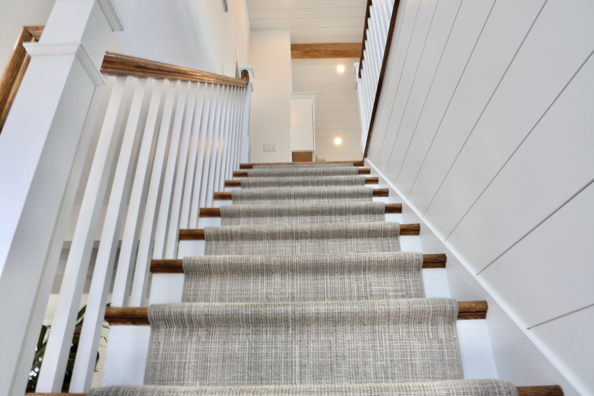 A staircase with a carpet on the steps and a white railing.
