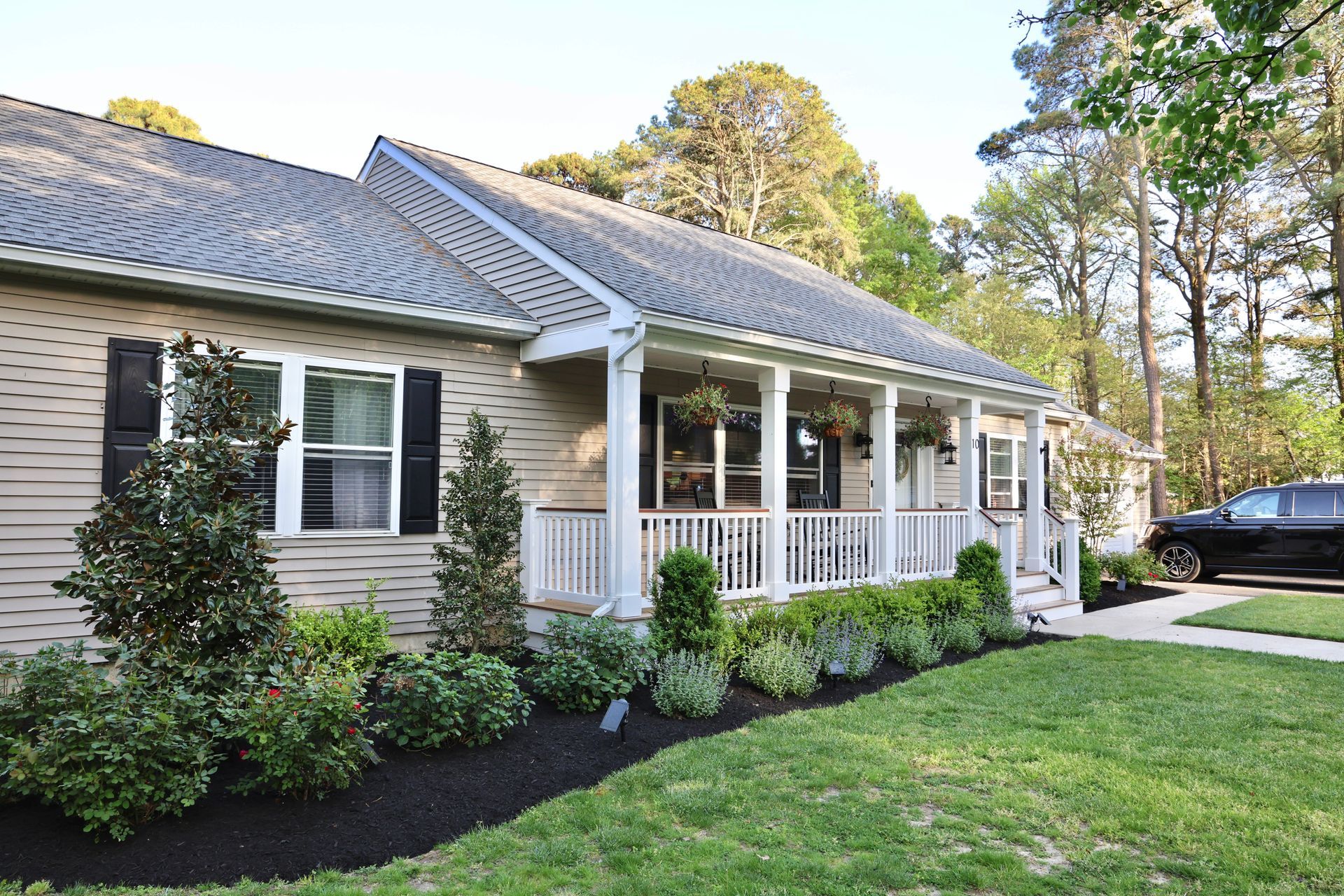 A house with a large porch and a car parked in front of it.