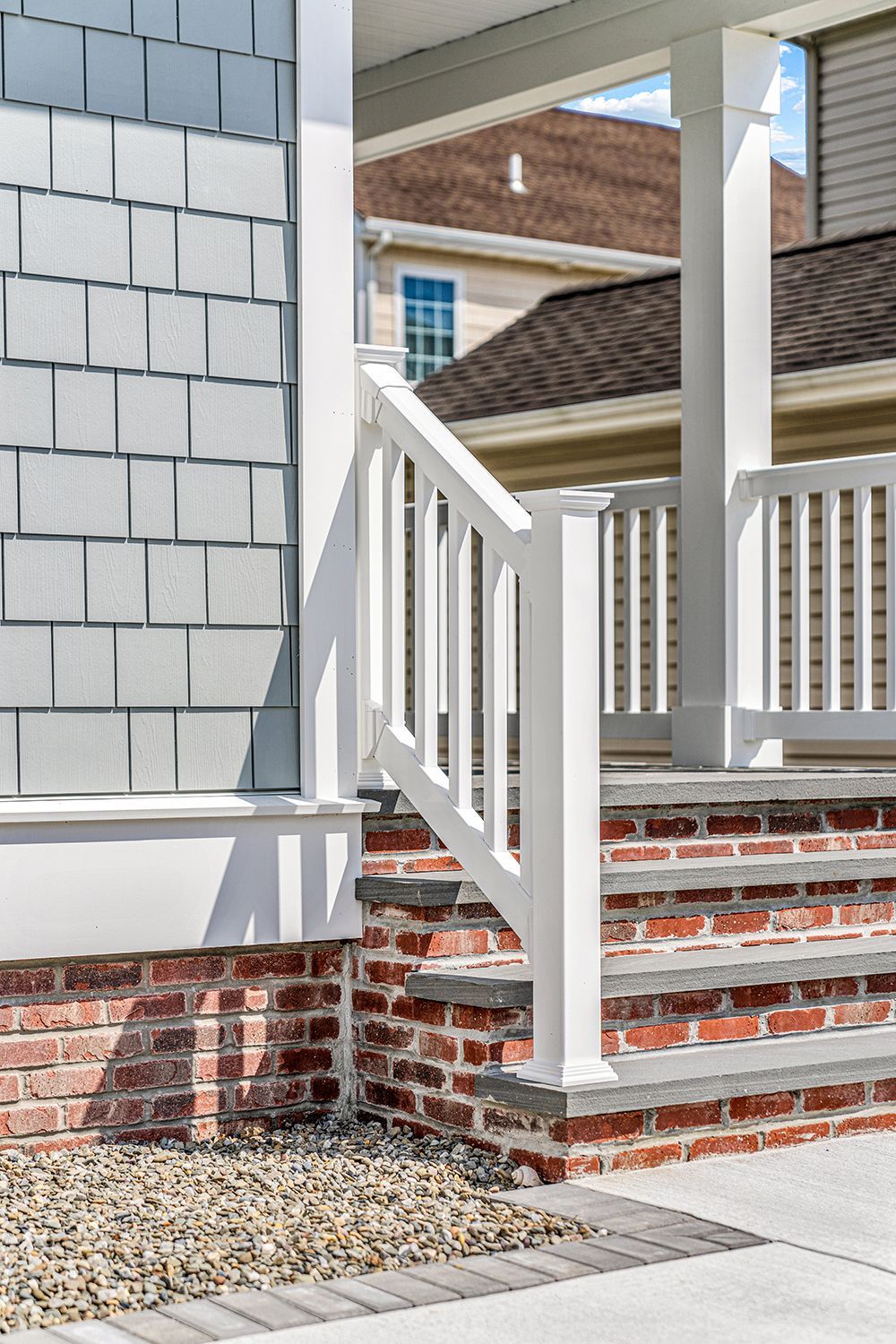 a white railing on a brick porch next to a house