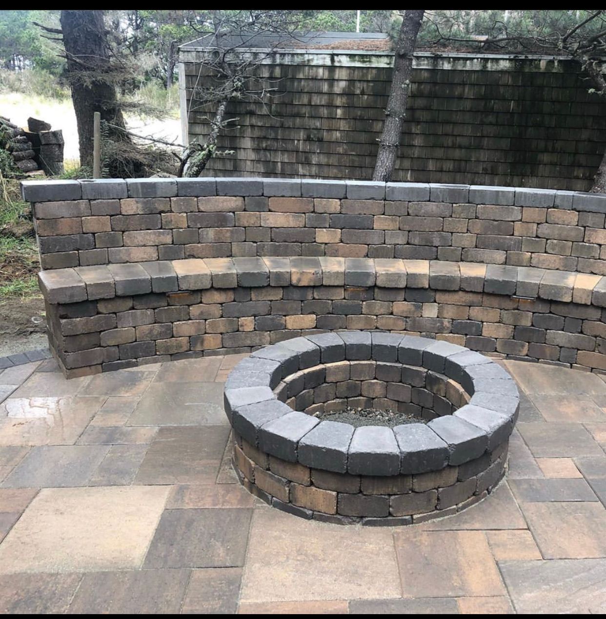 Curved brick seating wall around a circular fire pit on a stone patio outdoors