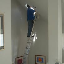 A man is standing on a ladder in a room.