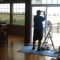 A man is standing on a ladder in front of a sliding glass door.