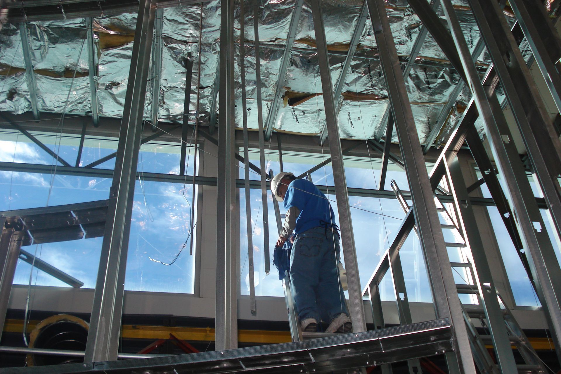 A man is standing on a ladder in a building under construction.