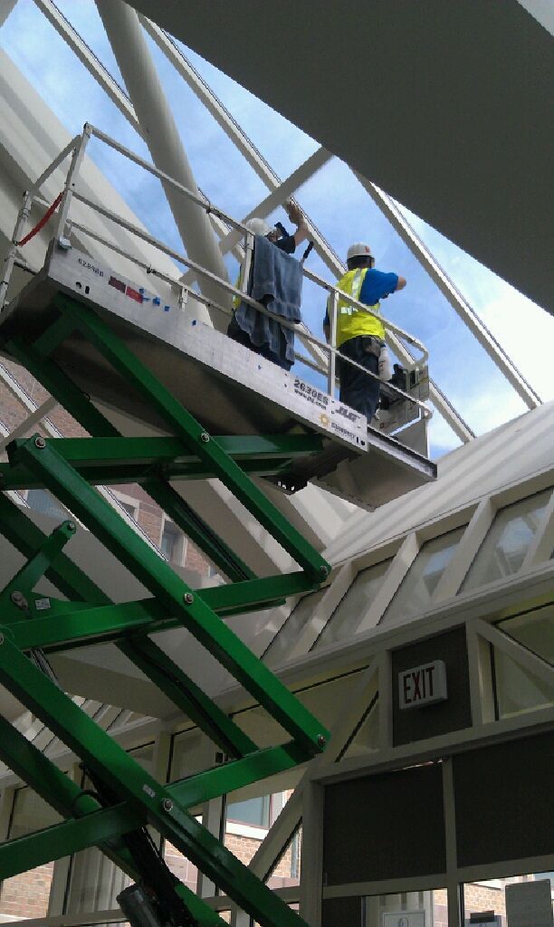 Two men are working on a green scissor lift.