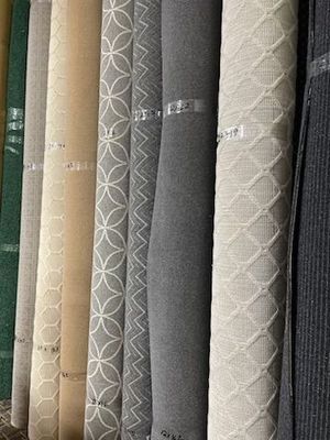 Close-up of rolled carpet samples in various neutral colors, including gray, beige, and patterned white.