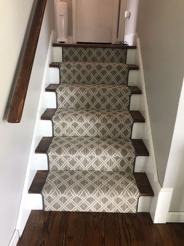 Staircase with patterned carpet runner, dark wood treads, and white risers. Handrail on the left.