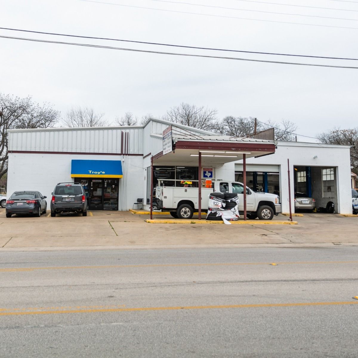 White auto repair shop with vehicles parked outside.