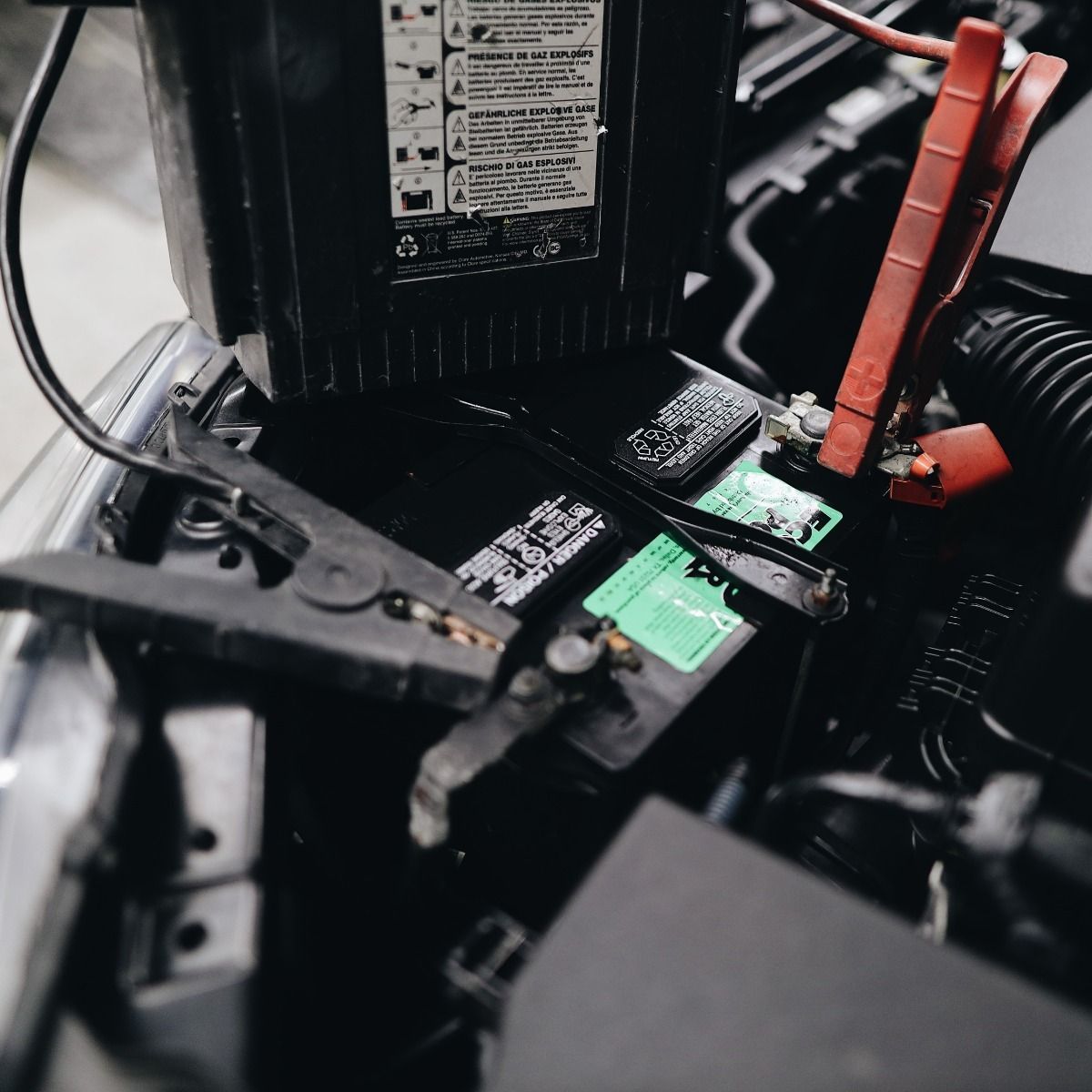 Car battery being jump started with jumper cables.