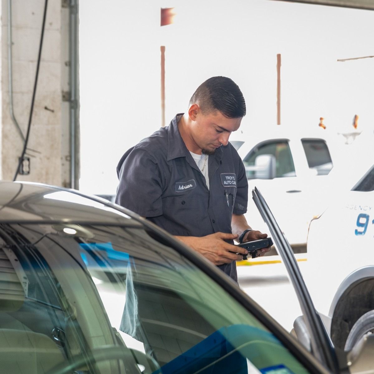 Mechanic using a diagnostic tool on a car in a garage.