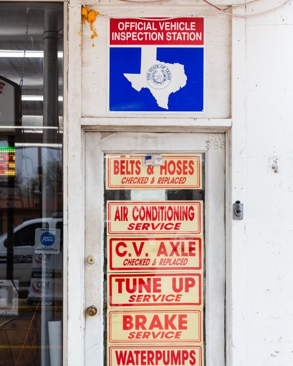 Door of a Texas vehicle repair shop with inspection station sign, and services like brakes, belts, and AC.