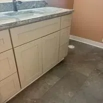 Bathroom cabinets with closed doors and a gray countertop.