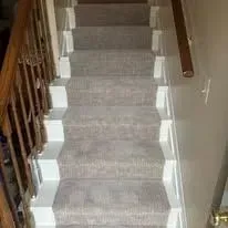 Staircase with gray carpet and white risers. Wooden railing on the left.