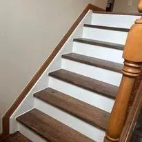 Wooden staircase with white risers and a wooden handrail.