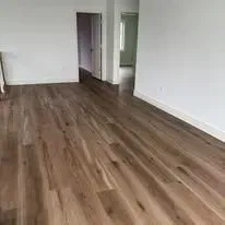 Hardwood flooring in a room with white walls, and a doorway.