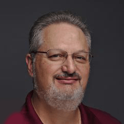 A man with a beard and glasses is smiling for the camera.