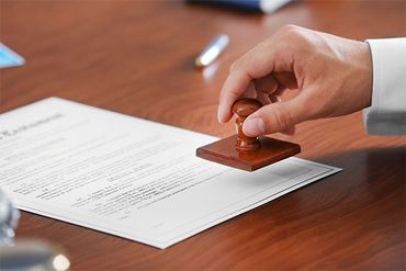 A person is stamping a document on a wooden table