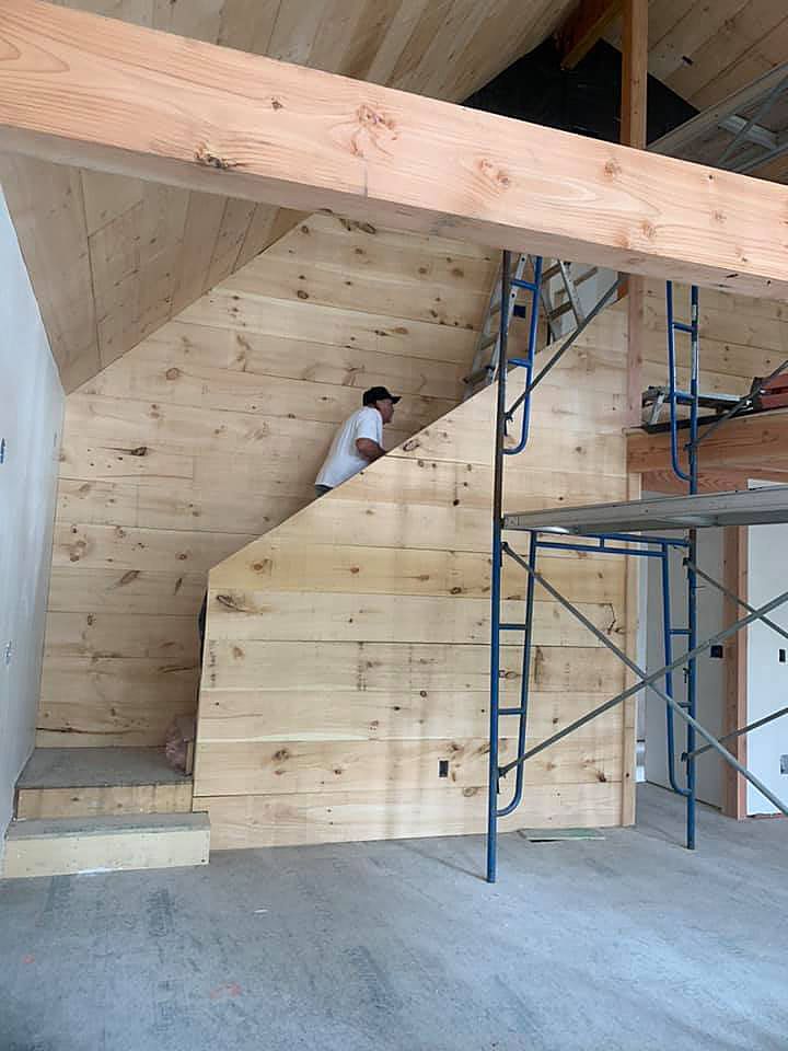 A man is standing on a wooden wall next to a staircase.