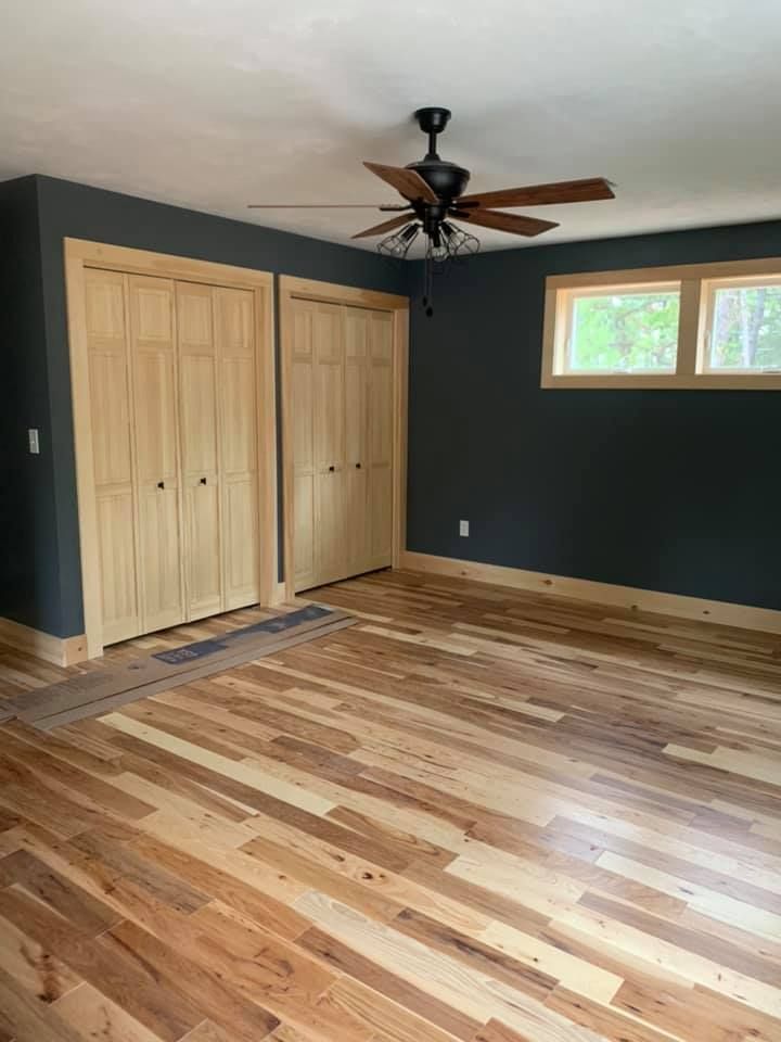 A bedroom with hardwood floors and a ceiling fan.
