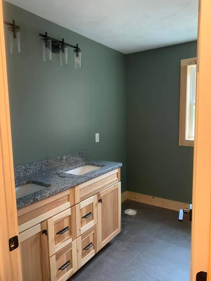 A bathroom with a sink , cabinets and a window.