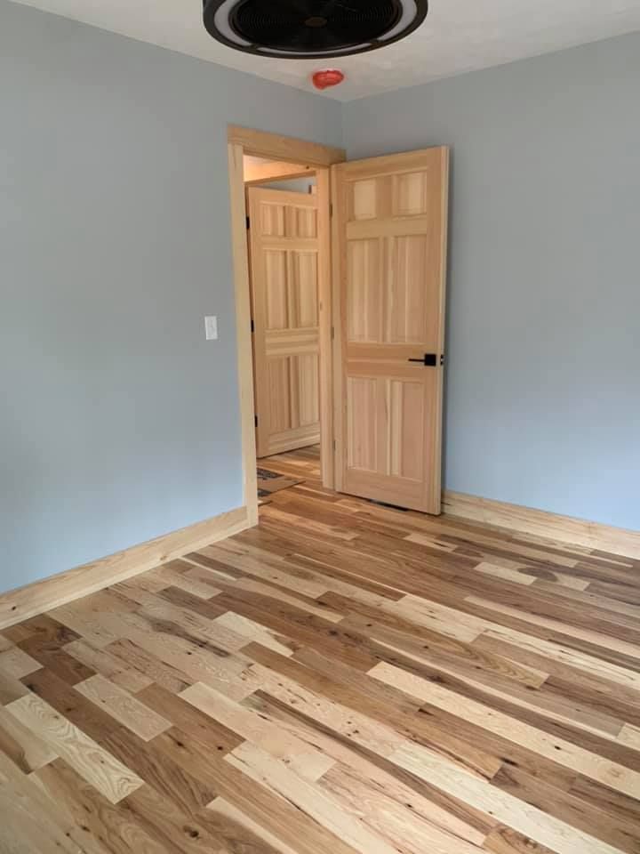 A bedroom with hardwood floors and a ceiling fan.