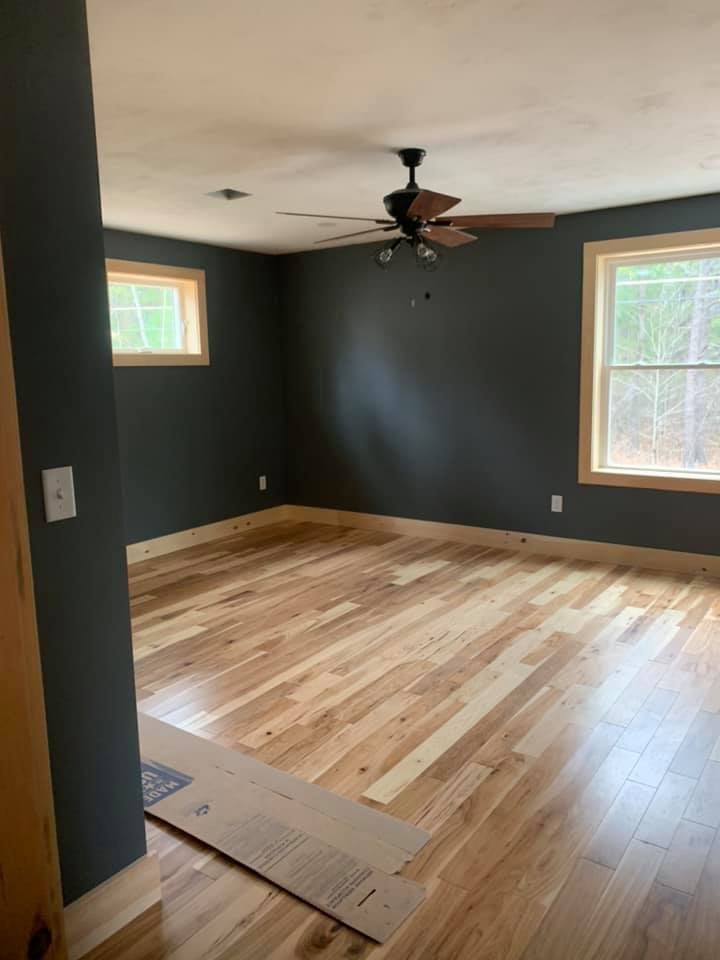 An empty room with hardwood floors and a ceiling fan.