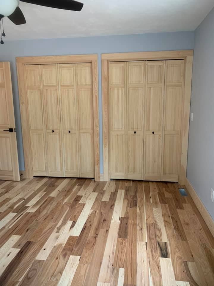 A bedroom with hardwood floors , closets , and a ceiling fan.