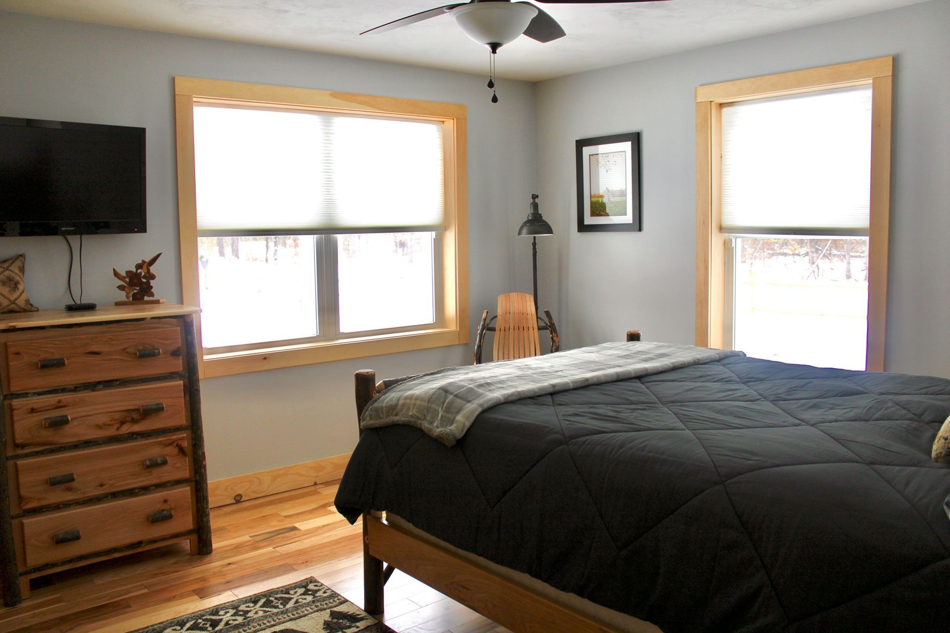 A bedroom with a bed , dresser , television and a ceiling fan.
