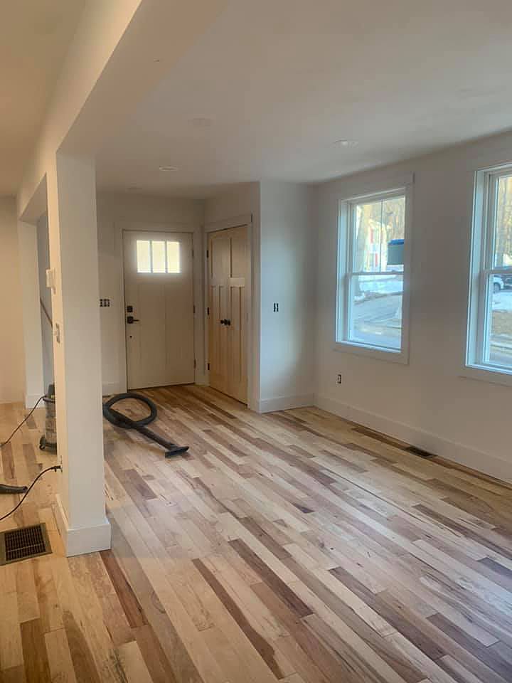 A living room with hardwood floors and a vacuum cleaner on the floor.