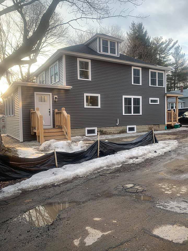 A large house with a lot of windows is being built on a snowy street.