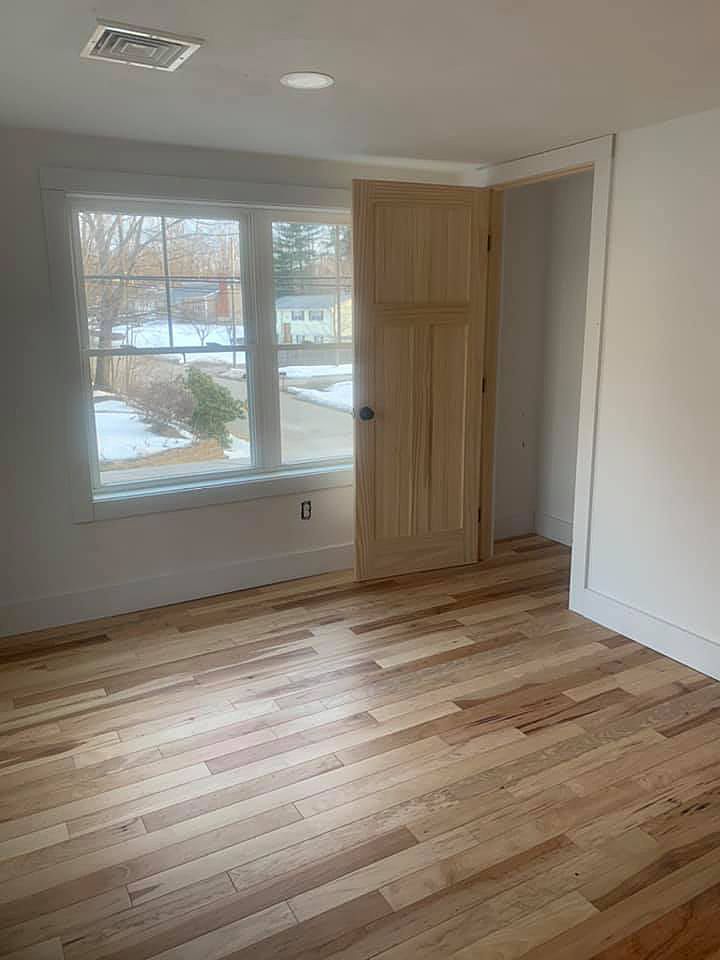 An empty room with hardwood floors and a window.