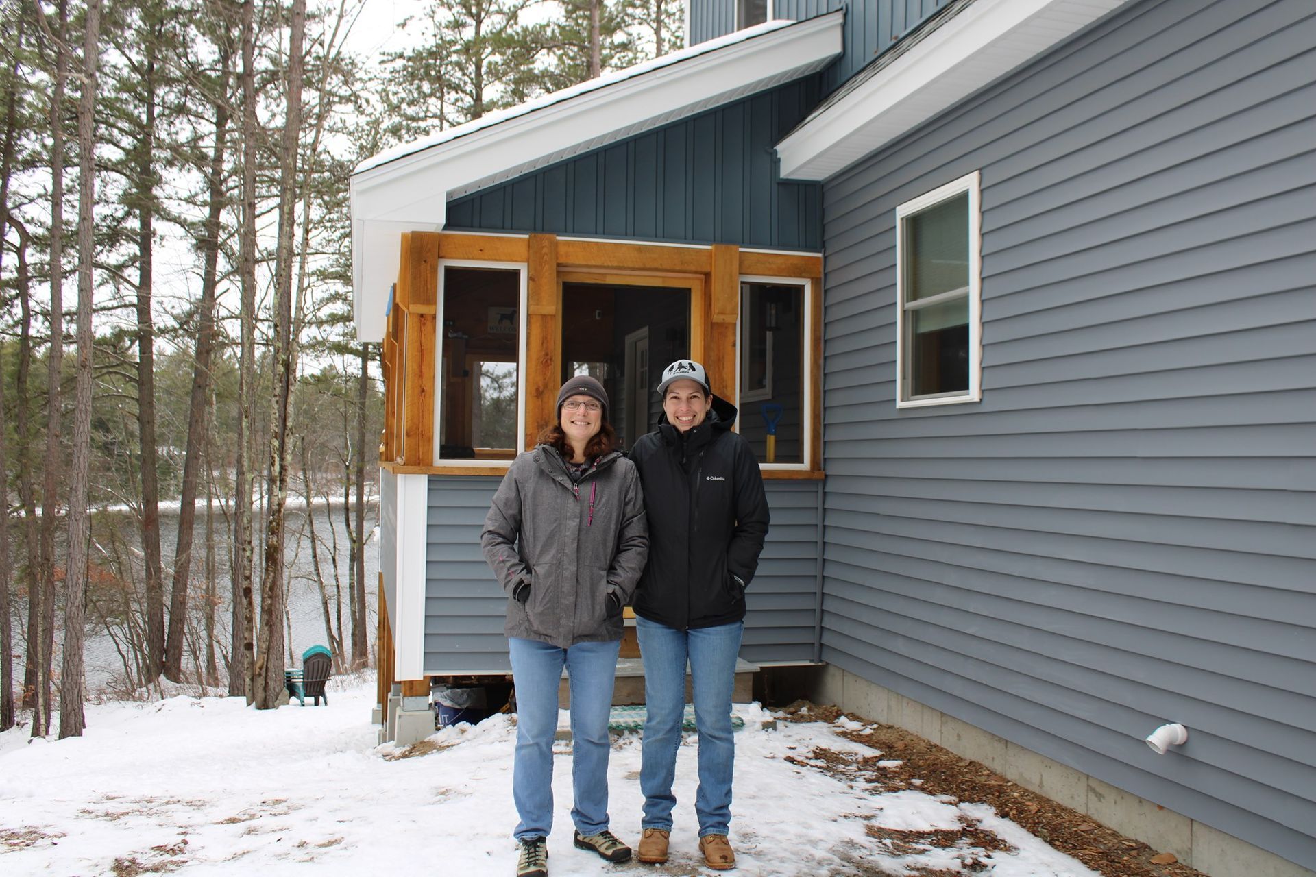 Two people standing in front of a house in the snow