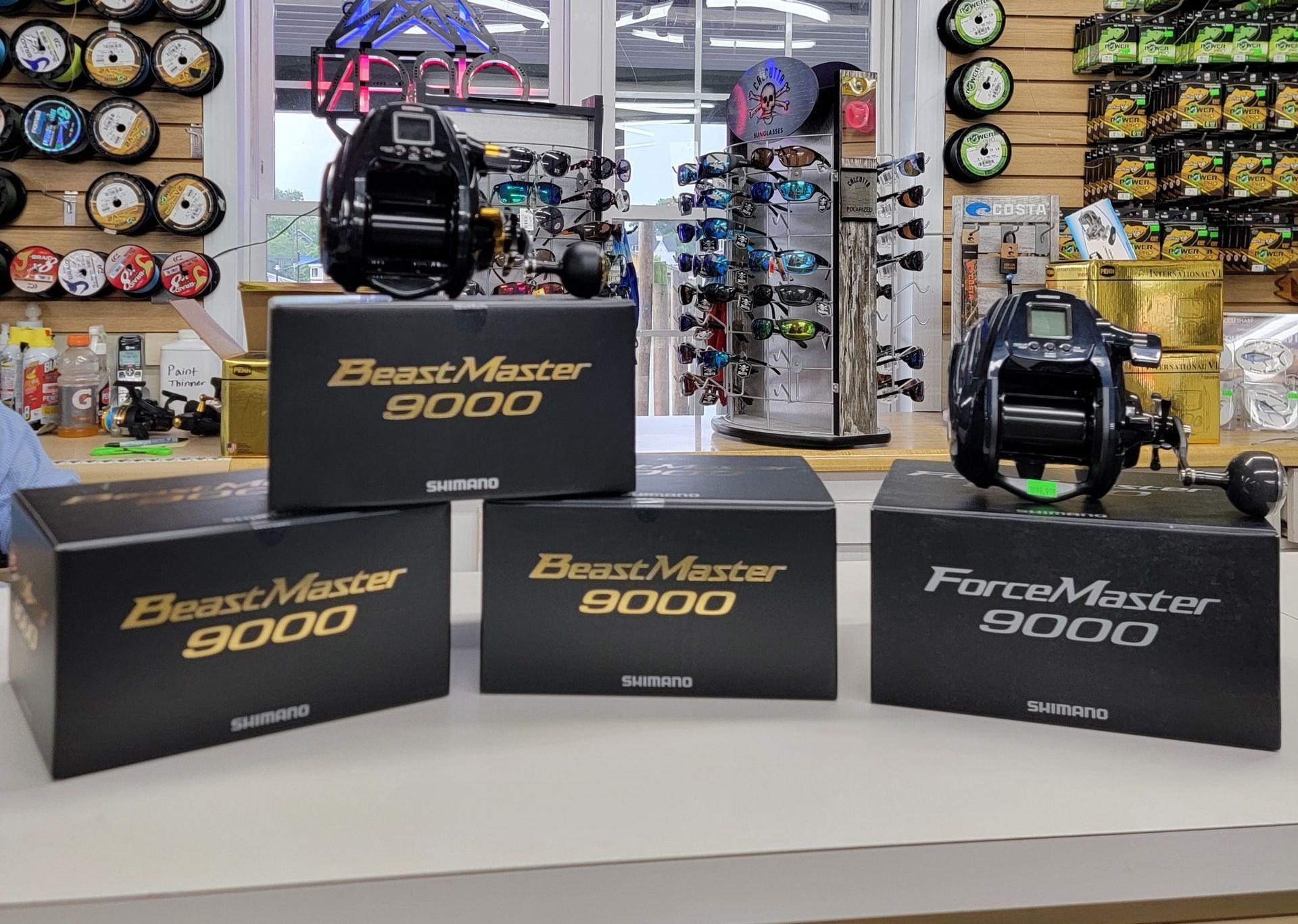 Three boxes of fishing reels are sitting on a table in a store.