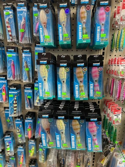 A bunch of fishing lures are hanging on a wall in a store.