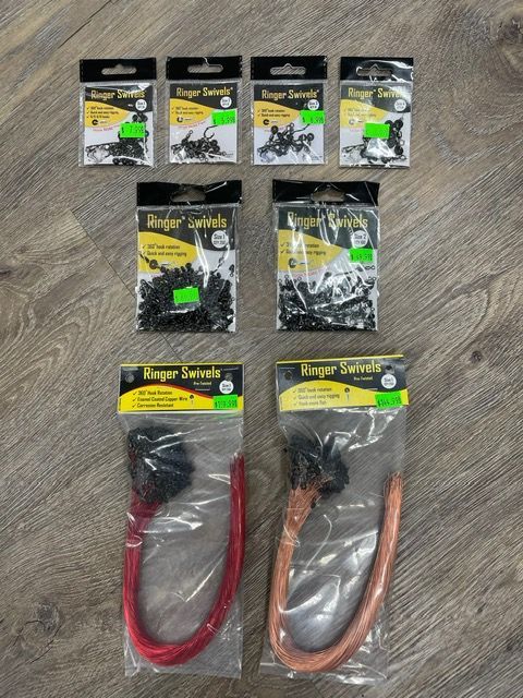 A bunch of different types of fishing hooks are sitting on a wooden table