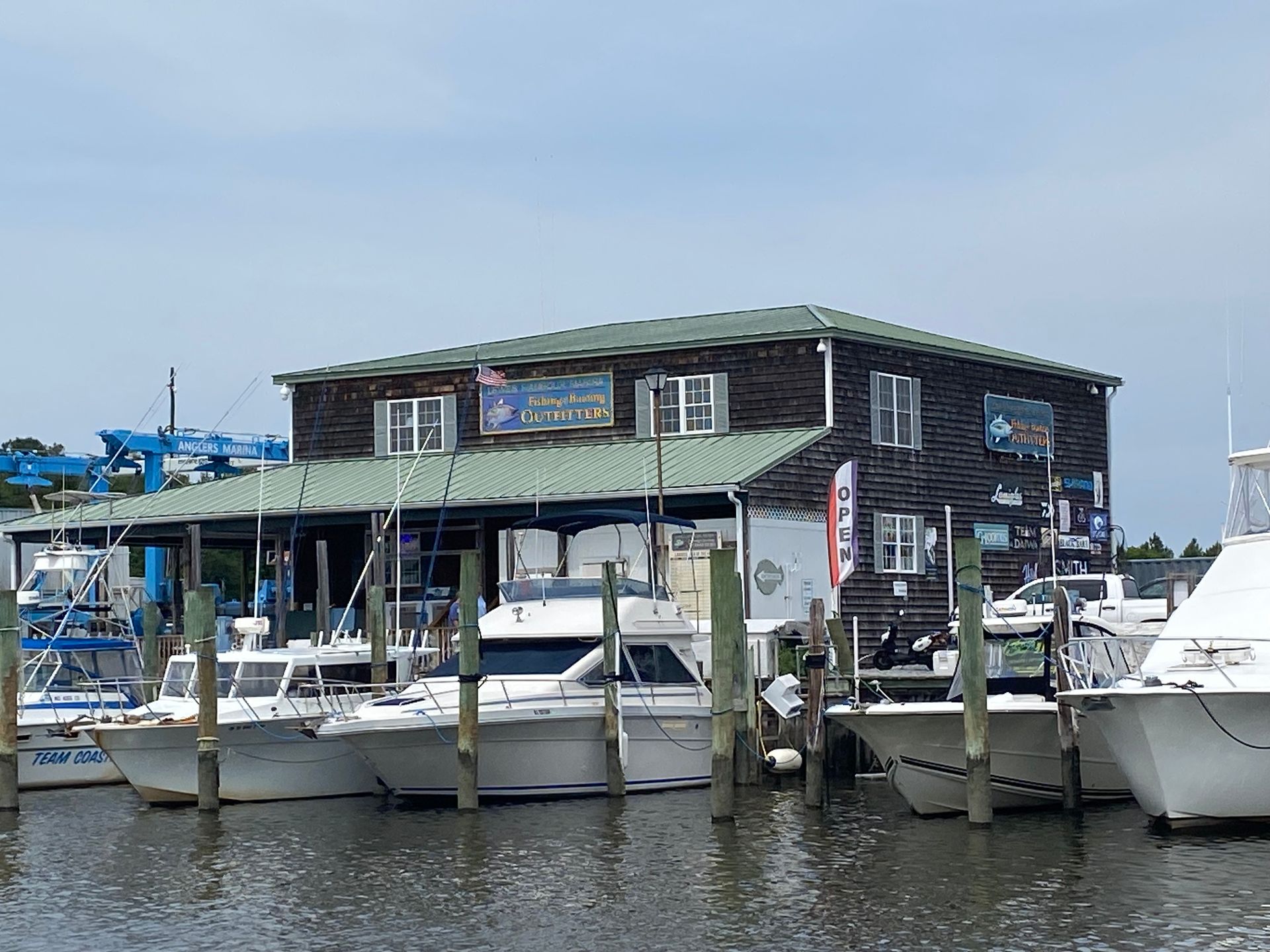 A row of boats are docked in front of a building on the water.