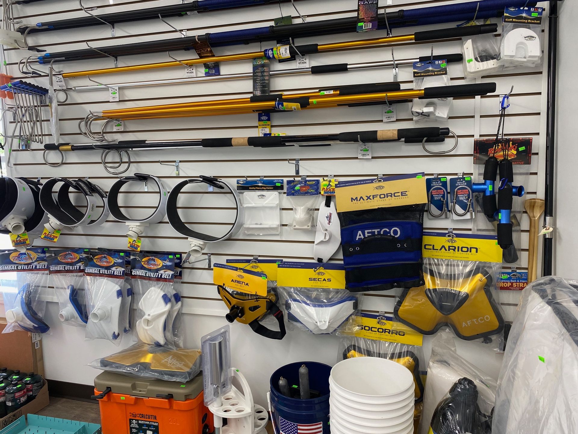 A wall filled with fishing rods , buckets , and other fishing equipment.