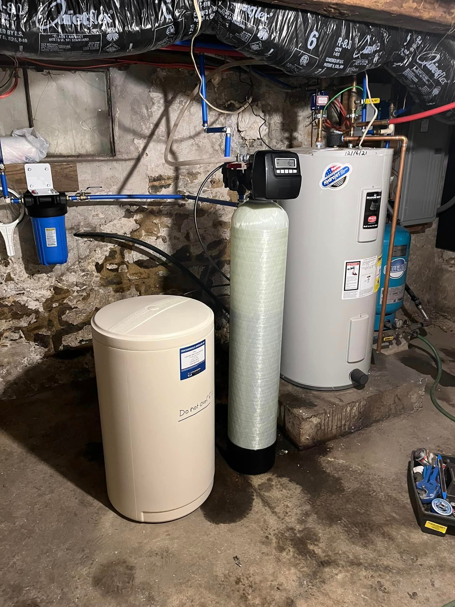 A water softener and a water heater are sitting in a basement.