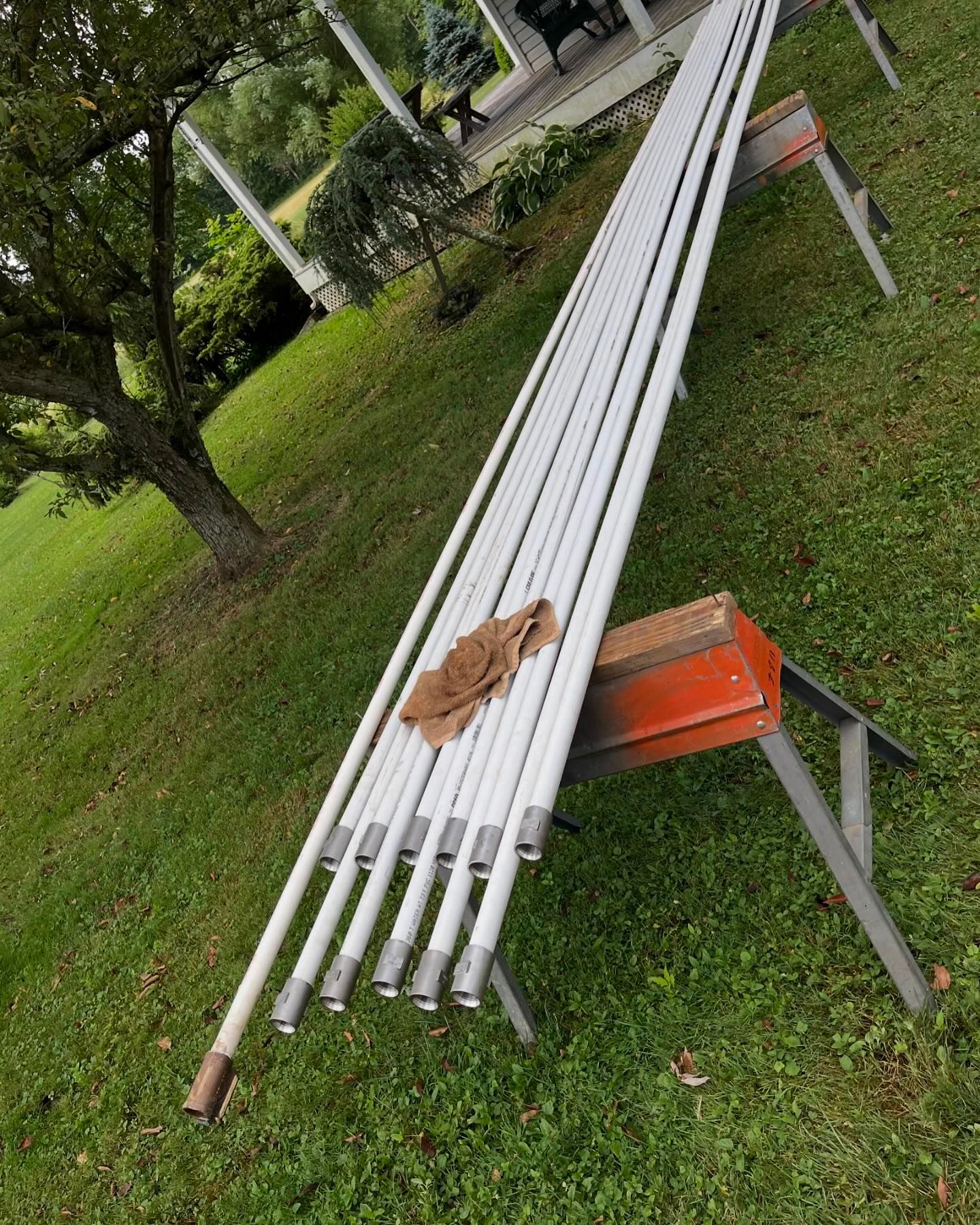 A bunch of white pipes are sitting on top of a stool in the grass.