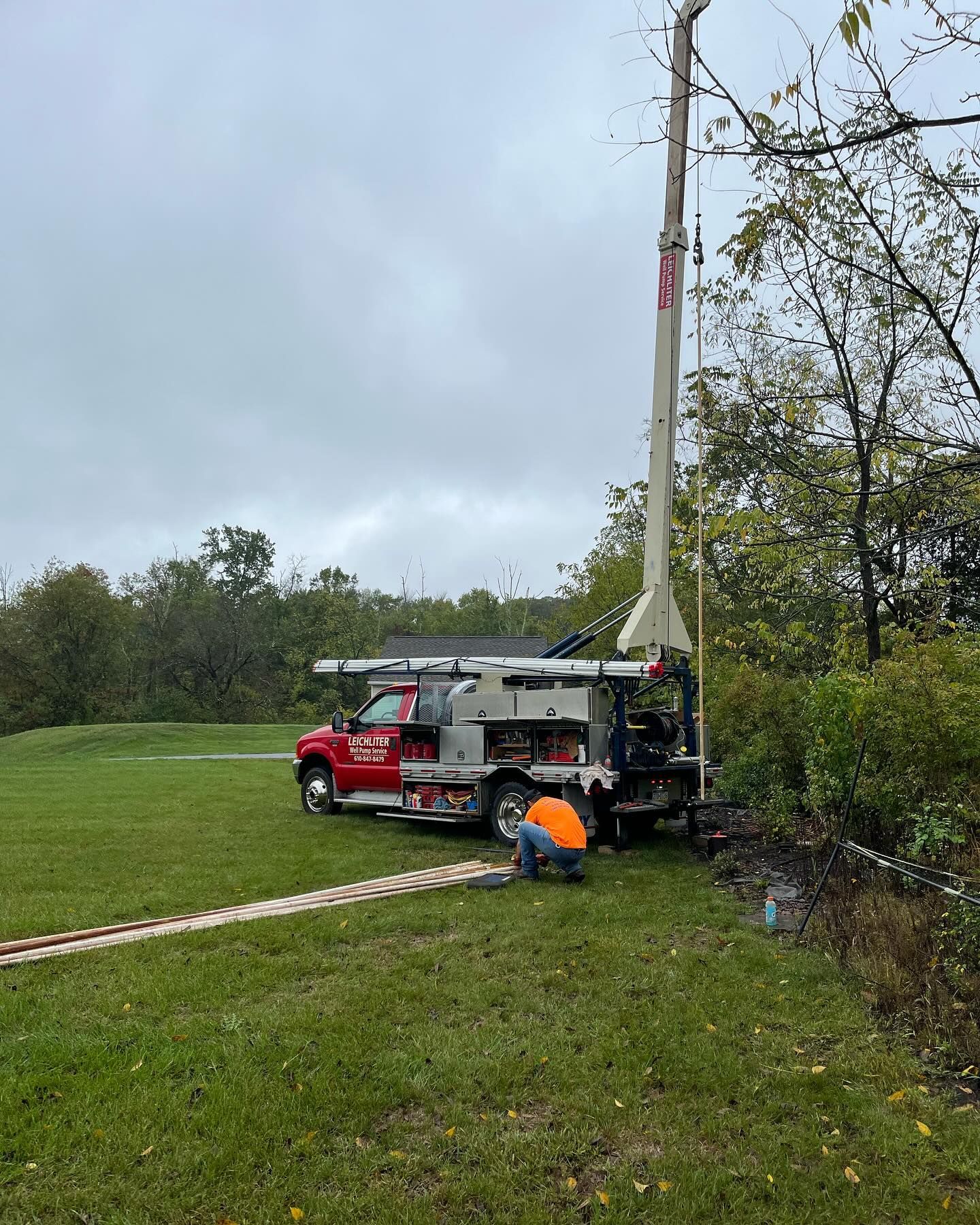A man is kneeling next to a truck in a field.