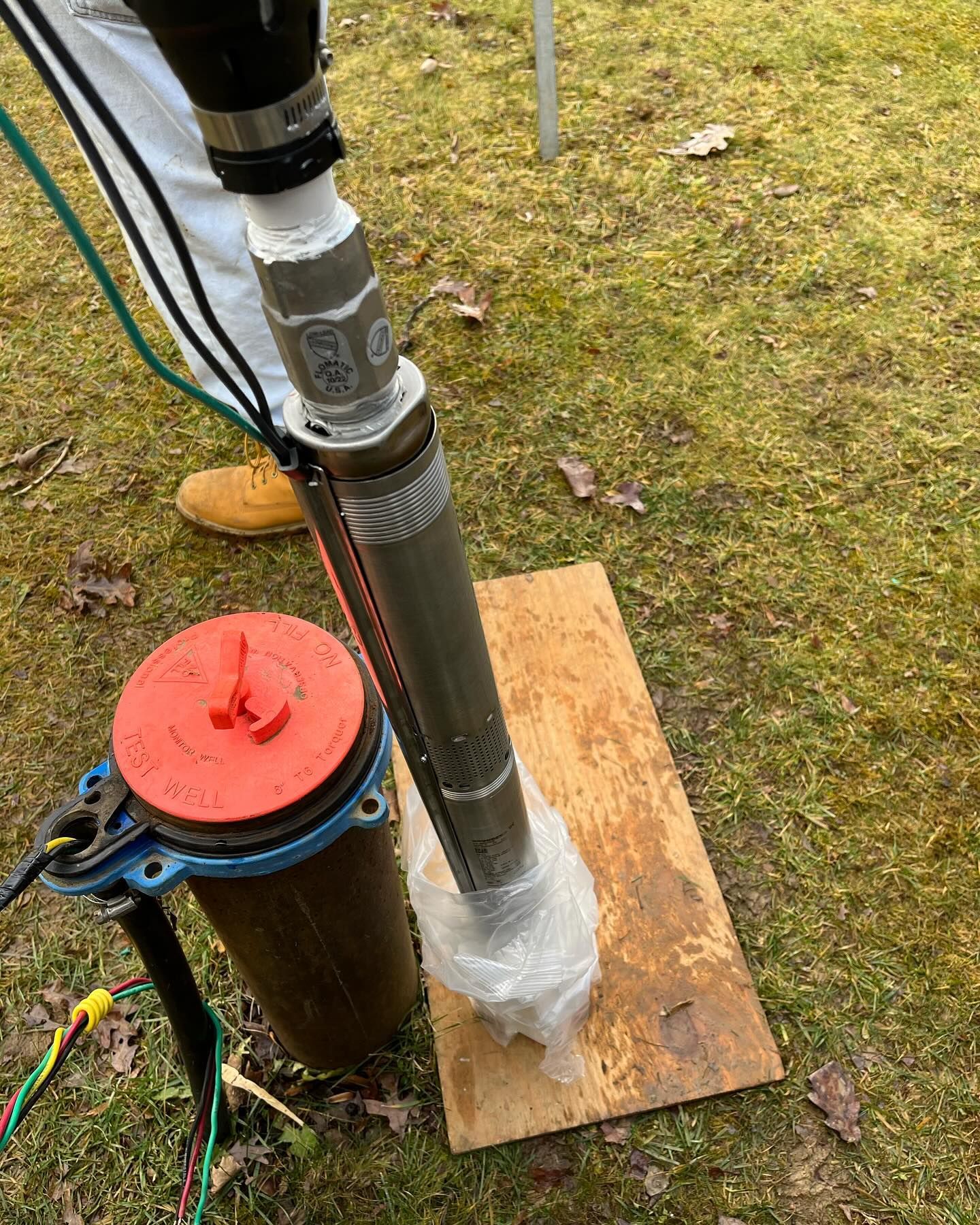 A person is standing next to a water pump on a wooden platform.