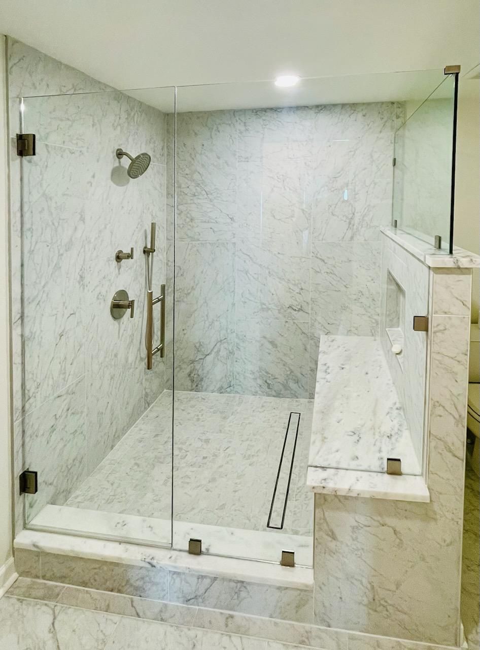 A bathroom with a walk in shower with a glass door