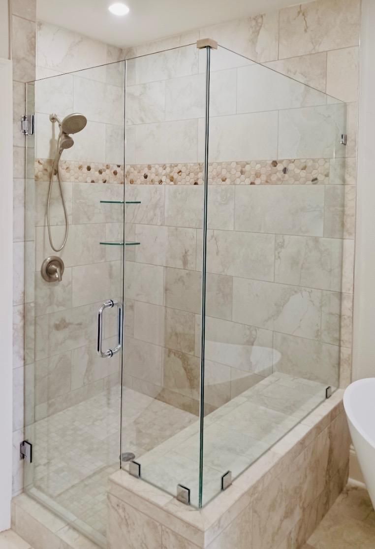A bathroom with a glass shower door and a bathtub