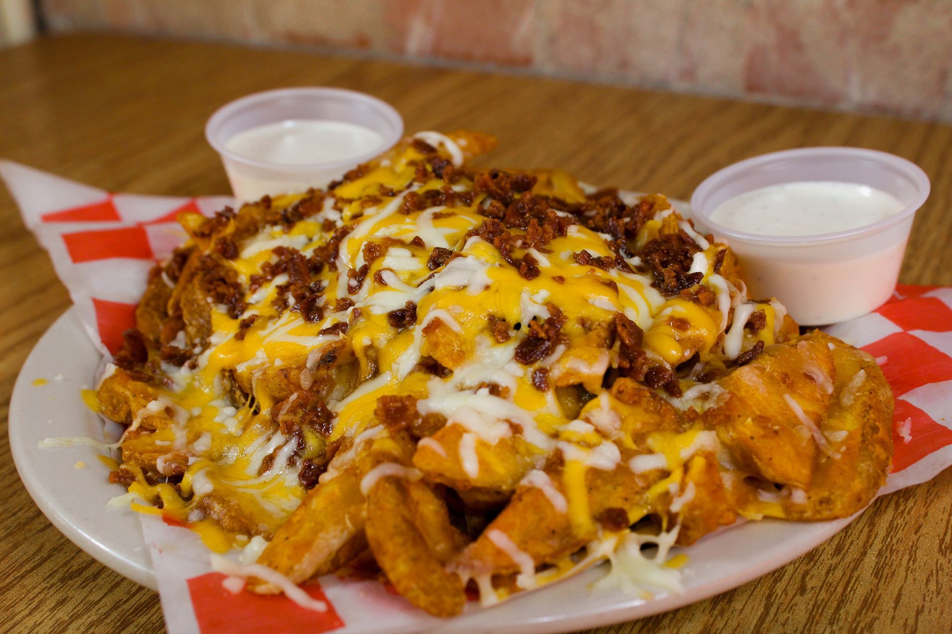 A plate of chicken fries with cheese and bacon on a wooden table.