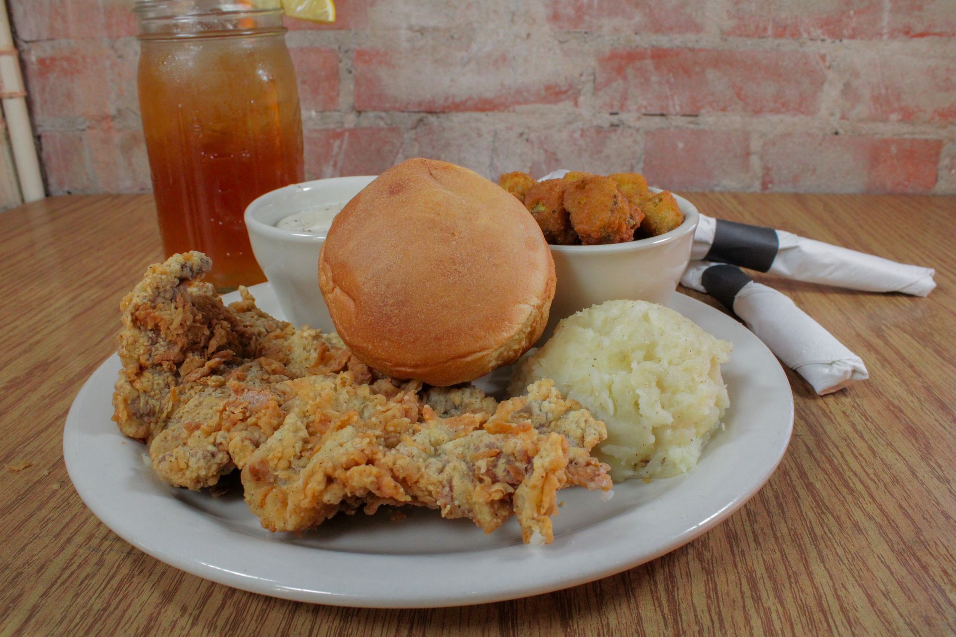 A white plate topped with fried chicken , mashed potatoes , a hamburger , and a drink.